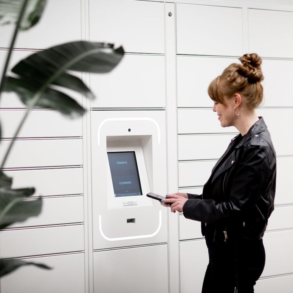 Woman collecting parcale from Grondfloor lockers with a smart phone