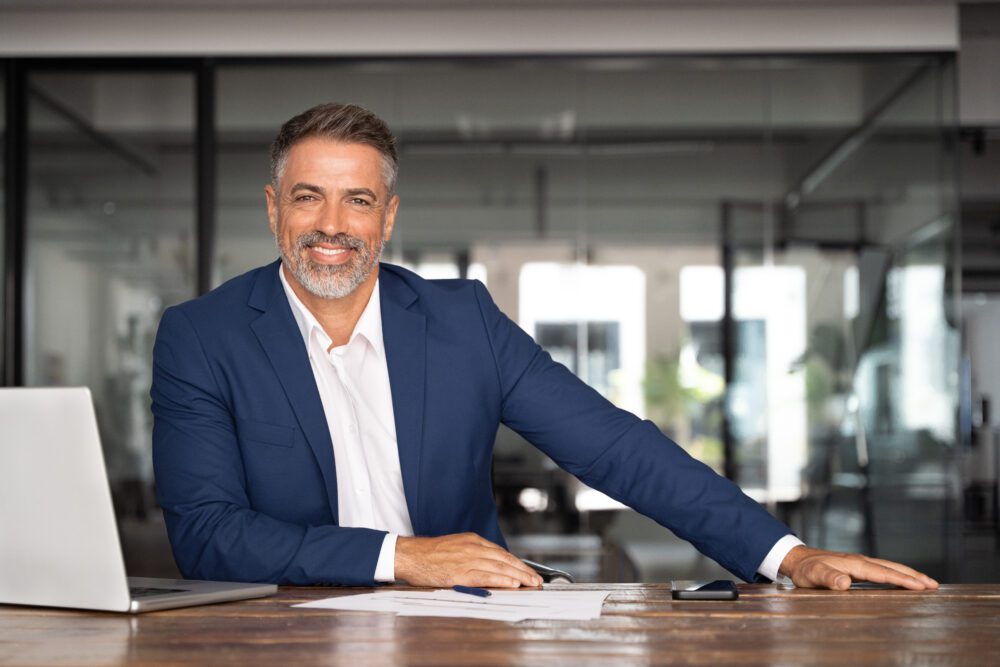 A man at a desk smiling about the comprehensive building management software features that make his day easier